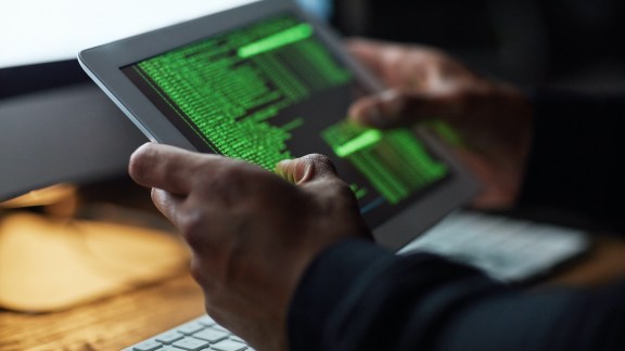 Cropped shot of an unidentifiable hacker cracking a computer code in the dark