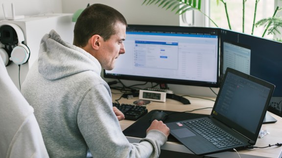 Young man using a laptop and computer at home