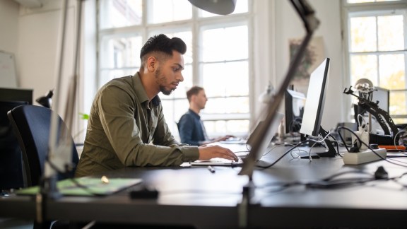 Young man busy working on laptop in office 