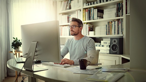 Cropped shot of a man sitting behind his computer in his home office