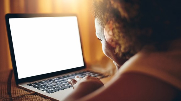 Rearview shot of a young woman using a laptop at home