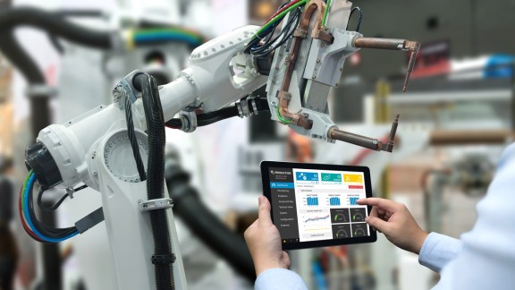 Engineer hand using tablet, heavy automation robot arm machine in smart factory industrial with tablet real time monitoring system application. Industry 4th iot concept.