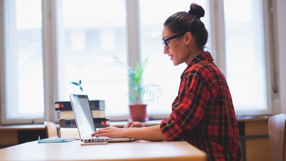 Young hipster girl working on laptop in the office