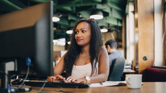 Young businesswoman using computer at desk in creative office