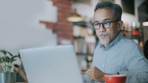 an asian chinese senior man having discussion with his colleague via online virtual meeting