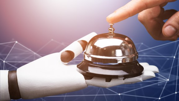 Close-up Of A Person Ringing Service Bell Hold By Robot Against Technology Background