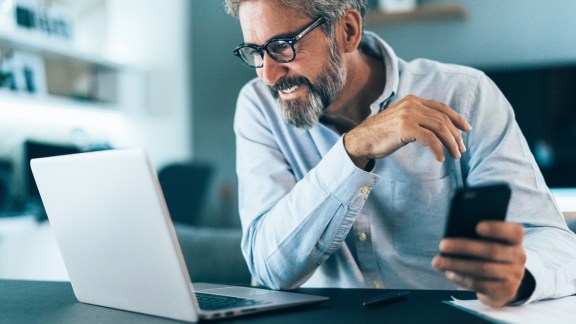 Mature businessman working at home using lap top and smart phone