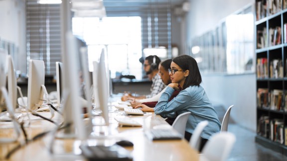 Shot of a group of university students working on computers in the library at campus