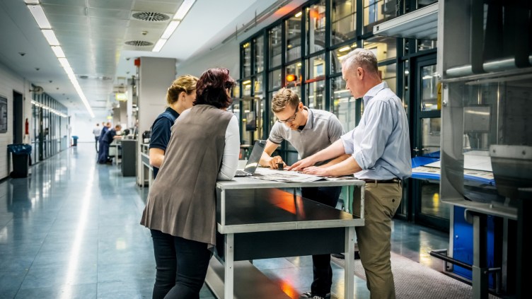 Business meeting of staff and management in a printery close to a production line