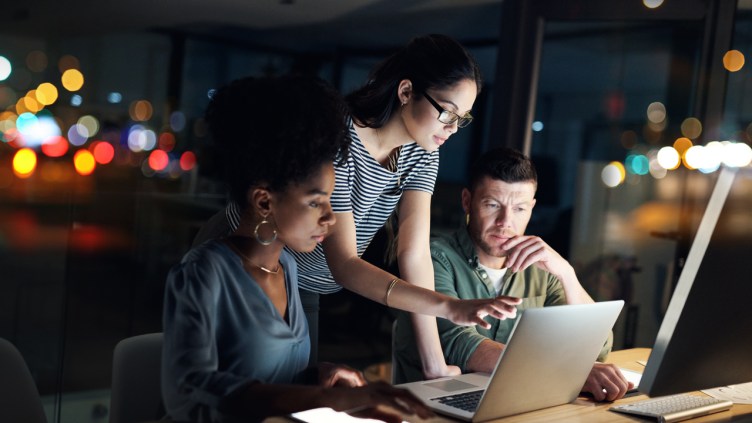 Shot of a group of designers working late on a laptop in an office