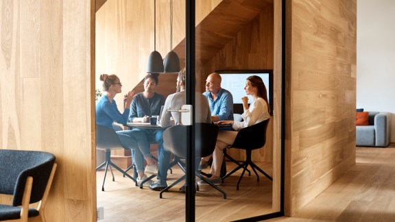 Business professionals discussing in meeting seen through glass door at office