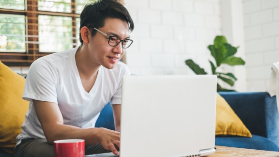 Young Asian man working with laptop at home