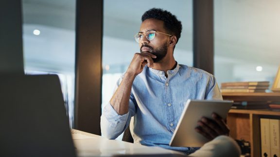 Shot of a young businessman using a digital tablet in an office at night