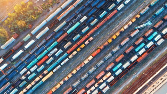 Top view of colorful cargo trains. Aerial view from flying drone of colorful freight trains on the railway station. Wagons with goods on railroad. Heavy industry. Industrial conceptual scene. Vintage