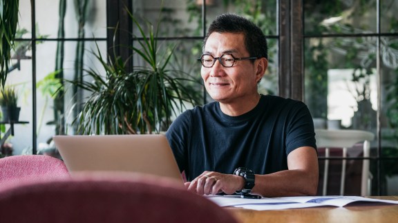 Mature man in glasses at home, typing on computer, contented, small business owner