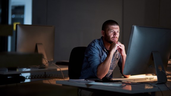 Shot of a businessman using a computer during a late night at work in a modern office