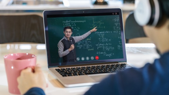 Rear View of Asian student learning with teacher on black board via video call conference when Covid-19 pandemic, education and Social distancing concept